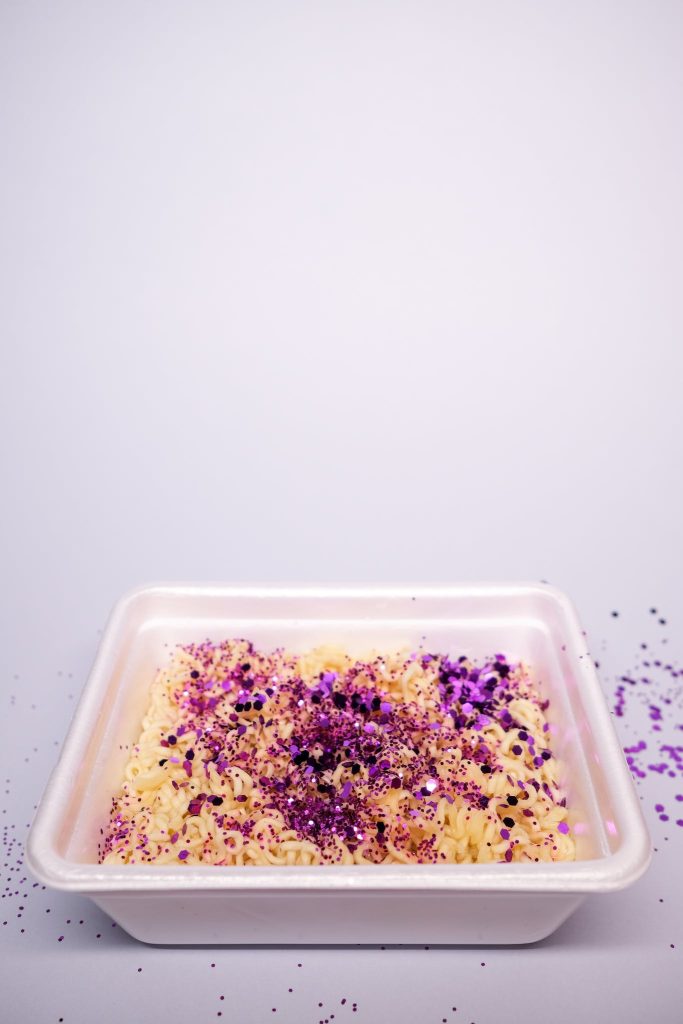 Asian instant noodles in simple plastic container on white table