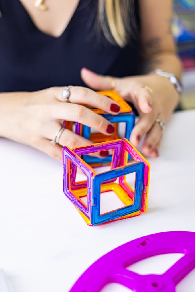 An adult playing with colorful magnetic blocks on a white table in São Paulo.